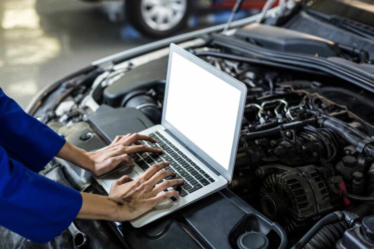 A professional auto electrician performing ADAS calibration in Sheffield using a diagnostic laptop on a vehicle with the bonnet open to ensure sensor accuracy.