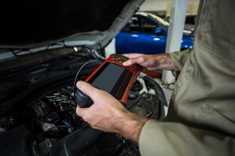A mobile auto electrician using a professional tablet diagnostic tool on a vehicle with the bonnet open to identify electrical faults in Sheffield.
