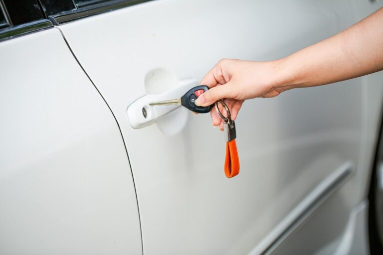 Auto electrician holding car keys next to a vehicle door after a professional central locking repair in Sheffield.
