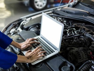 A professional auto electrician performing ADAS calibration in Sheffield using a diagnostic laptop on a vehicle with the bonnet open to ensure sensor accuracy.