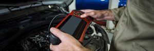 A mobile auto electrician using a professional tablet diagnostic tool on a vehicle with the bonnet open to identify electrical faults in Sheffield.