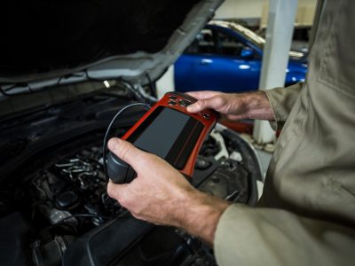 A mobile auto electrician using a professional tablet diagnostic tool on a vehicle with the bonnet open to identify electrical faults in Sheffield.