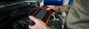 A mobile auto electrician using a professional tablet diagnostic tool on a vehicle with the bonnet open to identify electrical faults in Sheffield.