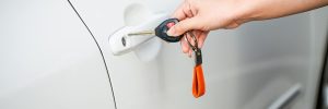 Auto electrician holding car keys next to a vehicle door after a professional central locking repair in Sheffield.