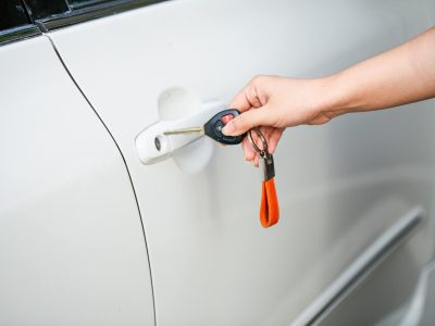 Auto electrician holding car keys next to a vehicle door after a professional central locking repair in Sheffield.