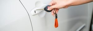 Auto electrician holding car keys next to a vehicle door after a professional central locking repair in Sheffield.